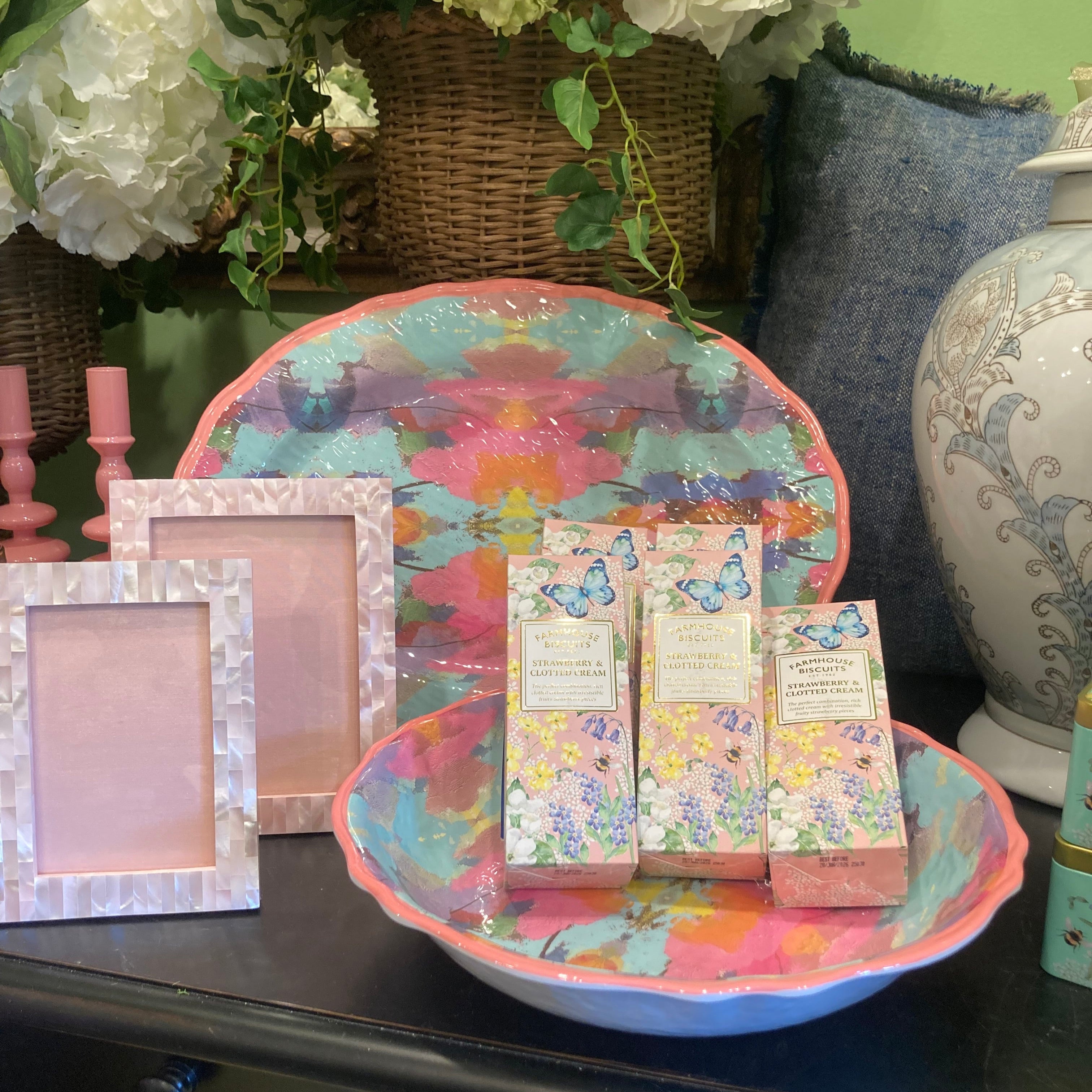 Decorative items including a colorful round tray with boxes, a square frame, and flowers on a surface.