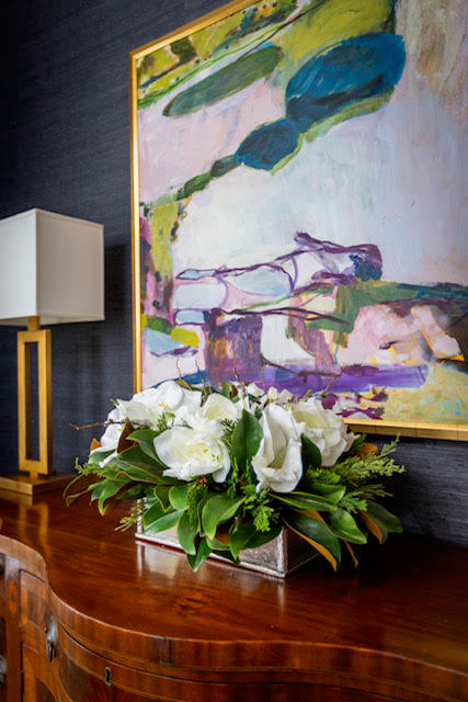 Floral arrangement on a wooden surface with abstract painting in the background