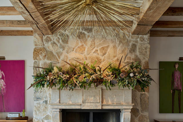 Decorative fireplace with stone surround and festive garland, wooden beams above.